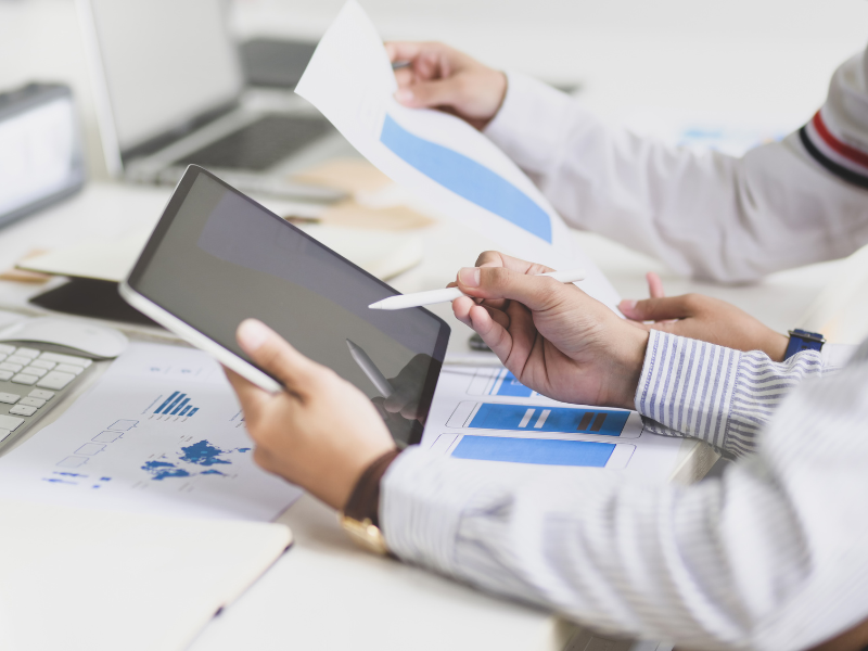 photo of a table with printed graphs and a tablet